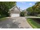 Exterior view of a brick home with a spacious driveway leading to a side-entry garage and mature landscaping at 1210 Brooks Ave, Raleigh, NC 27607