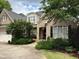 Charming brick home features a well-manicured lawn, mature trees, and a welcoming front porch at 1210 Brooks Ave, Raleigh, NC 27607