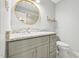 Well-lit bathroom features a granite countertop, grey vanity and a round mirror at 124 Twin Oaks Pl, Cary, NC 27511