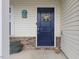 Close-up of a welcoming front door with a decorative wreath, brick accents, and charming mailbox at 13 Toplanders Ter, Gibsonville, NC 27249