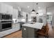 A modern kitchen is shown with an island, stainless steel appliances, white cabinetry, and wooden flooring at 147 Gentry Dr, Pittsboro, NC 27312