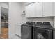 Well-lit laundry room with a sink, modern washer and dryer set, and storage cabinets for organized convenience at 147 Gentry Dr, Pittsboro, NC 27312