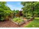 Backyard featuring raised garden beds, mulch, and lush landscaping, enclosed by a wood fence at 150 Teal Dr, Youngsville, NC 27596