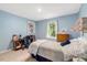 Cozy bedroom with blue walls, light wood floors, and a bed with blue and white patterned bedding, also includes desk at 150 Teal Dr, Youngsville, NC 27596