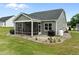 A home's backyard with a screened-in porch, black grill, green grass, and rock lined flower beds at 206 Heart Pine Dr, Wendell, NC 27591