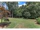 This backyard with mature trees has a green lawn and flowerbeds for added color and charm at 212 Fieldtrial Cir, Garner, NC 27529