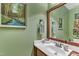 Cozy powder room featuring a modern sink, decorative mirror, and a painting on a green wall at 212 Fieldtrial Cir, Garner, NC 27529