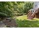 Enjoy the tranquility of this backyard featuring a wooden staircase leading to the deck and a quaint garden area at 215 Collinson Dr, Chapel Hill, NC 27514