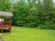 Expansive backyard with a covered deck, lush green lawn, and mature trees at 215 Virginia Pine Dr, Clayton, NC 27520