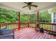 Charming covered deck with red painted wood, ceiling fan, and view of the trees at 215 Virginia Pine Dr, Clayton, NC 27520