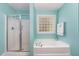 Bright bathroom featuring a soaking tub, walk-in shower, and glass block window at 25 Spicetree Ct, Youngsville, NC 27596