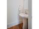 Clean half bathroom featuring a white pedestal sink and hardwood flooring at 253 Tobacco Farm Way, Chapel Hill, NC 27516