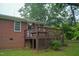 Exterior view of a brick home with a wooden deck and lush green lawn, complemented by mature trees at 2626 Crestline Ave, Raleigh, NC 27603
