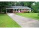 Quaint brick home featuring a driveway and covered parking, surrounded by a lush green lawn and mature trees at 2626 Crestline Ave, Raleigh, NC 27603