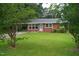 Charming brick home with a well-kept lawn, framed by lush trees, and showcasing blossoming bushes at 2626 Crestline Ave, Raleigh, NC 27603