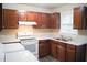 Functional kitchen featuring wood cabinets, white appliances, and durable countertops, ideal for culinary endeavors at 2626 Crestline Ave, Raleigh, NC 27603