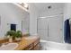 Well-lit bathroom with double sinks, wood cabinets, and sliding glass doors to tub with shower at 2706 Montgomery St, Durham, NC 27705