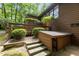 Side view of wooden house with stairs, deck and ground level door, surrounded by lush greenery at 2706 Montgomery St, Durham, NC 27705