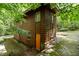 Side view of brown wooden home with orange door and surrounding green landscape with mature trees at 2706 Montgomery St, Durham, NC 27705