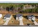Aerial view of a neighborhood with homes, driveways, yards, and a backdrop of lush green trees and blue sky at 274 E Boulder Road Rd, Henderson, NC 27537