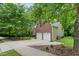 Side view of brick home with an attached two-car garage, lush landscaping and a sidewalk at 2801 Margots, Wake Forest, NC 27587