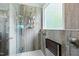 Modern tiled shower with a glass door, shower caddy, seating, and natural light from a window at 2801 Margots, Wake Forest, NC 27587