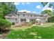 Back exterior view of home with large backyard and stone patio with lounge seating and dining area at 300 Bordeaux Ln, Cary, NC 27511