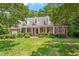 Charming brick home featuring a manicured lawn, lush landscaping, and a welcoming front porch at 300 Bordeaux Ln, Cary, NC 27511