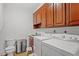 Functional laundry room with washer, dryer, sink, and wooden storage cabinets at 300 Bordeaux Ln, Cary, NC 27511