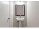 Small bathroom with a pedestal sink, decorative mirror and lighting, and white door and wall paint at 3325 Old Buffaloe Rd, Raleigh, NC 27604