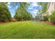 Expansive backyard featuring lush green lawn, mature trees, a trampoline and manicured landscaping at 4 Pickard Pl, Durham, NC 27703