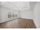 Spacious primary bedroom featuring tray ceiling, elegant light fixture and hardwood style floors at 4 Pickard Pl, Durham, NC 27703