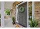 Close-up of a stylish front door with a green wreath, sidelights, and potted plants adding to the welcoming entrance at 4 Pickard Pl, Durham, NC 27703