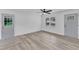 A view of the living room showcasing the wood flooring, windows, and a gray door at 460 Bunn Elementary School Rd, Bunn, NC 27508