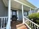 Inviting covered front porch featuring classic white columns, a wood floor, and a black front door at 479 Manchester Trail, Clayton, NC 27527
