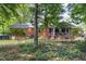 Rear view of brick home featuring a screened porch and a spacious backyard with mature trees at 4808 Berini Dr, Durham, NC 27705