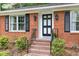 Charming brick home featuring a black front door with glass panes and black shutters on the windows at 4808 Berini Dr, Durham, NC 27705