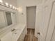 Bathroom with vanity, decorative mirror, open doorway, and white cabinets at 5614 Skyline Dr, Durham, NC 27712