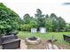 Relaxing backyard with comfortable seating around a stone fire pit near the sheds and mature trees at 601 Country Ln, Holly Springs, NC 27540
