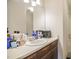 Bathroom vanity with a white sink and a wood base, featuring an array of toiletries on the counter at 601 Country Ln, Holly Springs, NC 27540