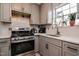 Kitchen with gray cabinets, stainless steel appliances, white countertop, and view to the window at 601 Country Ln, Holly Springs, NC 27540