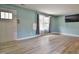 Bright living room with laminate flooring, a large window, and modern wall-mounted television at 601 Country Ln, Holly Springs, NC 27540