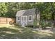 Charming storage shed in the backyard surrounded by green grass, landscaping, and a wooden fence at 6521 Sunset Manor Dr, Wake Forest, NC 27587
