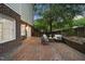 A brick backyard patio with outdoor seating, a lush tree, and a privacy fence at 704 Walcott Way, Cary, NC 27519