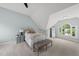 A bedroom with sloped ceilings, a white bed, and arched windows with backyard views at 704 Walcott Way, Cary, NC 27519