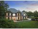 Beautifully lit brick home with mature landscaping, lush green lawn, and inviting architectural details at twilight at 704 Walcott Way, Cary, NC 27519