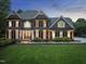 Stately brick home featuring manicured lawn, mature landscaping and elegant architectural details at 704 Walcott Way, Cary, NC 27519