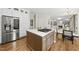 Spacious kitchen with hardwood floors, stainless steel refrigerator, and center island with a cooktop at 704 Walcott Way, Cary, NC 27519