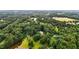 Aerial view showcasing a home enveloped by a dense canopy of trees, complemented by a serene pond at 7918 Dairy Ridge Rd, Mebane, NC 27302