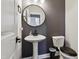 Powder room featuring a pedestal sink, oval mirror, and dark gray paint creating a sleek and modern atmosphere at 805 Winter Meadow Dr, Wake Forest, NC 27587